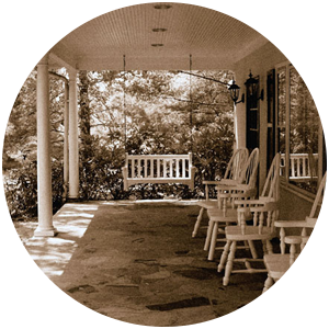 Sepia-toned photo of a porch with white chairs and a swing